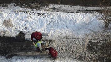 Woman workers break ice with crowbar on the road