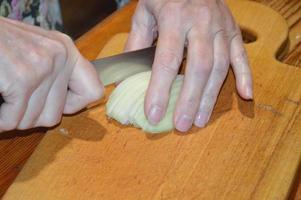 rebanar cebollas con un cuchillo sobre una tabla de cocina foto