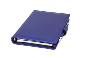 Diario de cuello azul y bolígrafo colocado en la portada y fondo blanco. foto