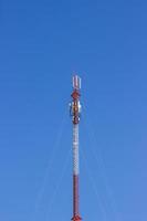 Torre de telecomunicaciones roja y blanca en un día de cielo azul claro. poste de teléfono foto