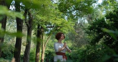 Female practicing qigong and meditation in summer park or forest photo