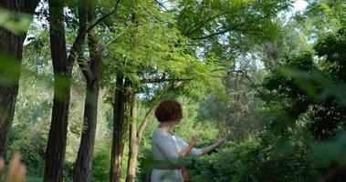 Female practicing qigong and meditation in summer park or forest photo