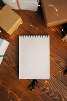 Flat lay of blank notebook and gift boxes on wood table background. photo