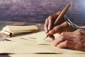 mujer mayor escribiendo a mano una carta con una pluma estilográfica foto