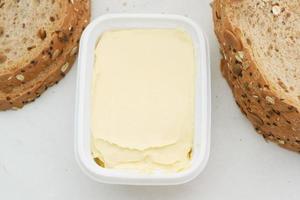 fresh butter in a container with bread on white background photo