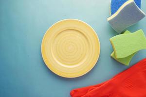 sponge , rubber gloves and colorful plate on pink photo