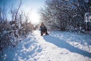 Mom rides with her son on a sled from a hill. photo