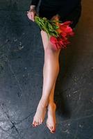 Pattern of Beautiful slim smooth woman's legs after laser hair removal on the rude cement background with tulips flowers photo