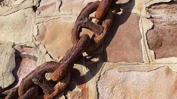 Rusty metal anchor chain on a natural granite wall background. Retro, vintage, nautical illustration