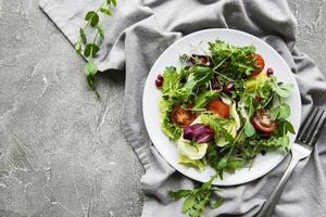 Ensalada mixta verde fresca con tomates y microgreens sobre fondo de hormigón. comida sana, vista superior. foto