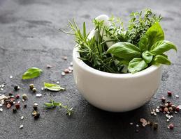 Bunch of aromatic herbs in mortar on a black concrete background photo