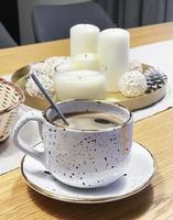 Cup of coffee on the table and a tray with candles photo