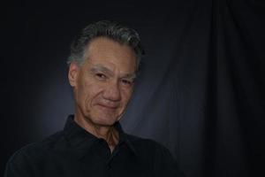 Dramatic Portrait of a Mature Man against a Black Background wearing a Black Shirt photo