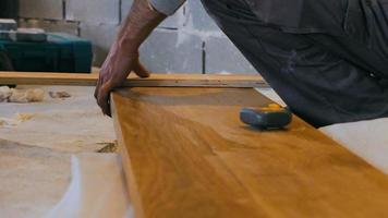 carpinteiro profissional de ladrilhos mede e marca uma prancha de madeira no canteiro de obras video
