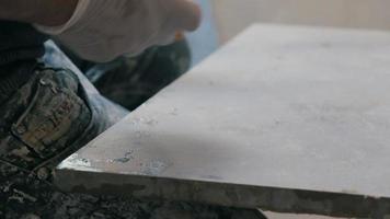 Professional tiling worker measures and marking a tile with pencil