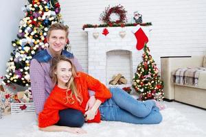 young couple at home with a fireplace and christmas tree photo