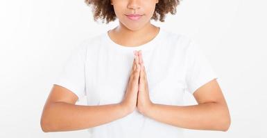Close-up of hands of black, afro american woman in white clothes meditating indoors, focus on arms in Namaste gesture. Healthy lifestyle concept. Mock up. Copy space. Template. Blank.