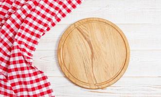 servilleta y tabla para pizza en primer plano de escritorio de madera, mantel. lienzo, paños de cocina en la vista superior de fondo de mesa de madera blanca simulacro. enfoque selectivo foto