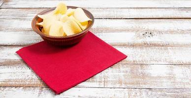 potato chips on plate and red napkin on wooden table - copy space photo