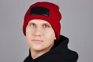 hipster in red hat and hoodie on gray background photo