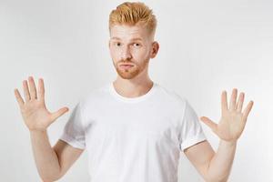 Hombre de pelo rojo con signo de calmarse - aislado, hombre mostrando signo de calmarse, concepto de miedo, por favor, tómatelo con calma, mantente fresco foto