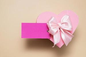 tarjeta rosa en blanco con caja de regalo en forma de corazón foto