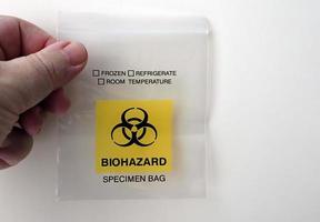 Male hand holding a Biohazard Specimen Bag on white background. Copy space for your text photo