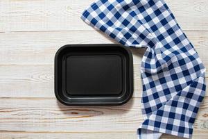 Empty black tray with checkered tablecloth top view on table photo