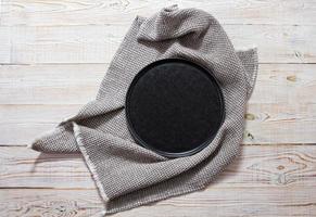 Black empty plate and tablecloth on wooden table Top view photo