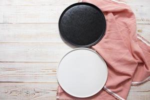black and white empty plate mock up top view on wooden table, table cloth napkin top view photo