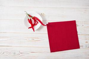 hot red pepper and paper napkin on old wooden table, holiday concept photo