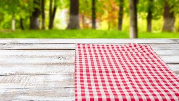 checkered tablecloth on a wooden table on blurred forest background photo