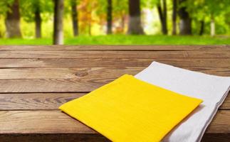 white and yellow napkin on empty wooden table on blurred park baclground,copy space,empty photo
