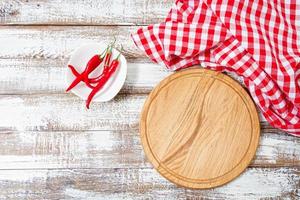 Vista superior mantel rojo arrugado, pimiento picante y plancha sobre mesa de madera, maqueta