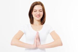 Girl in namaste gesture pose, closeup of beautiful European woman in white Tshirt isolated on white background practicing yoga and meditation, holding palms together in namaste mudra, with closed eyes
