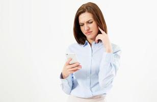 Upset woman holding a cellphone. Angry young businesswoman reading bad news on her cell phone. Isolated on white background. photo