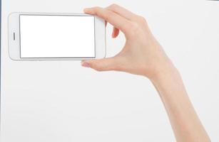 Hand holding white phone isolated on white clipping path inside. Top view.Mock up.Copy space.Template.Blank. photo
