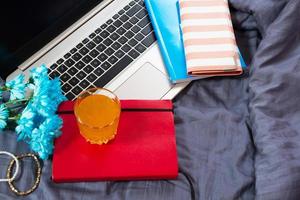 Work space at home, keyboard top view, female hand close up, notebook, work space on bed top view, flowers, colour background photo