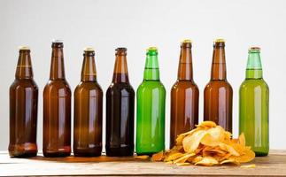 Beer bottles and potato chips on a wooden table. Top view. Selective focus. Mock up. Copy space.Template. Blank. photo
