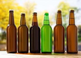 bottles of craft beer on wooden table on blurred park background photo