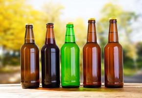 beer bottles on table on blurred forrest background, holiday concept photo