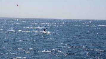 windsurfista che naviga veloce nel mar rosso vicino alla barriera corallina dei delfini. l'osservatorio sottomarino all'orizzonte.