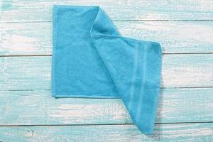 Blue towel top view on wooden blue board close up copy space. Blue soft napkin closeup photo