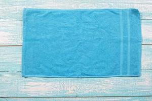 Blue towel top view on wooden blue board close up copy space. Blue soft napkin closeup photo