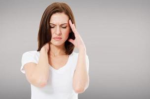 suffering brunette woman on grey background, headaches photo