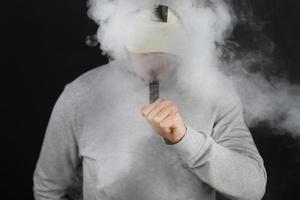 vaping man holding a mod cloud of vapor Black background isolated Selective focus photo