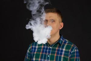 vaping man holding a mod cloud of vapor Black background isolated Selective focus photo