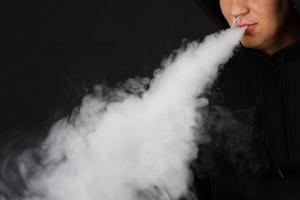 vaping man holding a mod cloud of vapor Black background isolated Selective focus photo