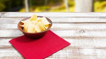 potato chips on plate and red napkin on wooden table - copy space photo