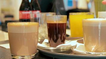 Se colocan muchos vasos con café y jugo en el mostrador de un café. video